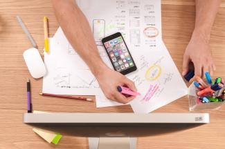 busy desk from above with man's hands taking notes